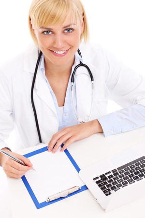 A picture of a young happy doctor with laptop and documents over white backgroundの写真素材