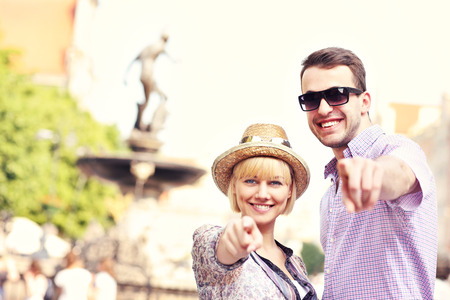 A picture of happy tourists pointing to the camera in front of Neptun Fountain in Gdansk Polandの写真素材