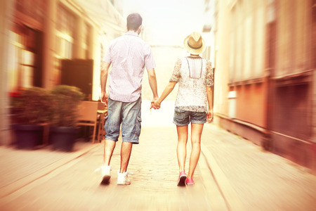 A picture of the back of a young couple strolling about the cityの写真素材