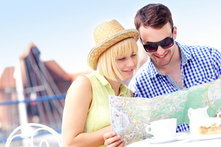 A picture of young tourists sitting with a map in a cafeの写真素材
