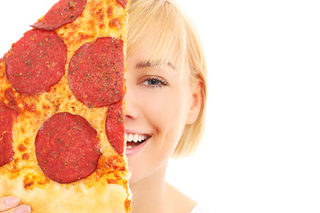 A picture of a happy woman covering her face with pizza over white backgroundの写真素材