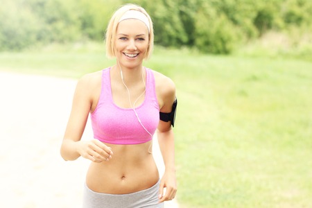 Nice young woman running in park with headphonesの写真素材