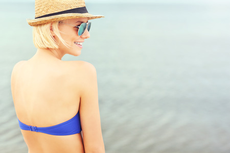 Young nice woman on the beach over sea from the backの写真素材