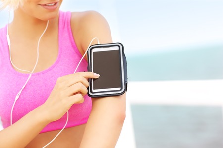 Close up of fit woman touching phone placed in armbandの写真素材