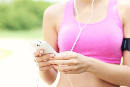 A midsection of a jogger with smartphone in the parkの写真素材
