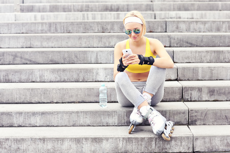 A picture of a roller skater resting on concrete stairs and using a cellphoneの写真素材