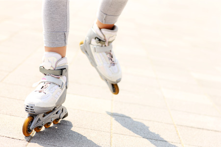A picture of woman's legs with roller blades on the path