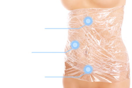 A picture of woman's body wrapped in foil over white backgroundの写真素材
