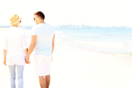 Back of a young couple walking at the beachの写真素材