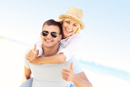 A picture of a happy couple showing ok sign at the beachの写真素材