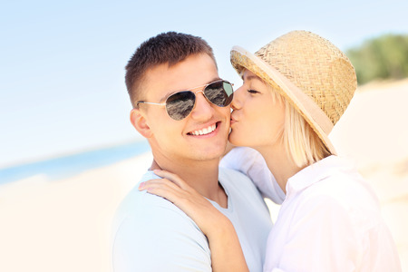 A picture of a woman kissing a man at the beachの写真素材