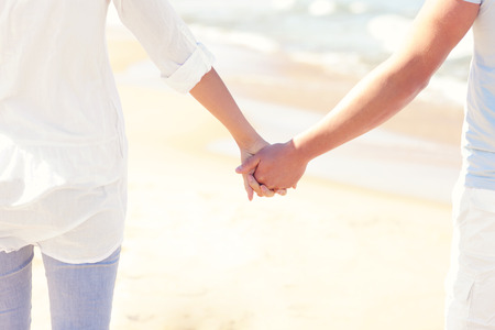 A picture of a young couple holding hands at the beach の写真素材