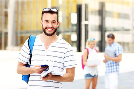 A picture of a young student standing and smiling in the campusの写真素材