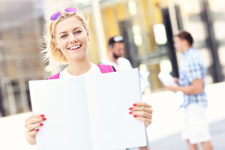 A picture of a young student standing in the campus with an open notebookの写真素材