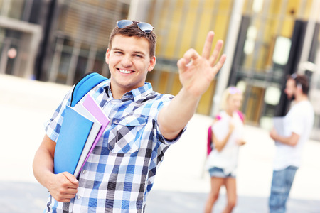 A picture of a young student showing ok sign in the campusの写真素材