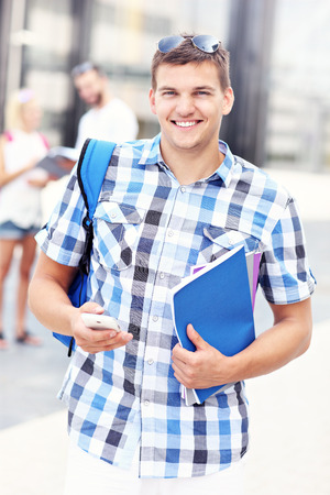 A picture of a young student standing and smiling in the campusの写真素材