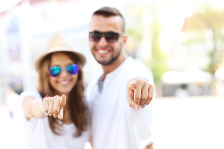 A blurry portrait of a couple pointing to the camera focus on fingersの写真素材