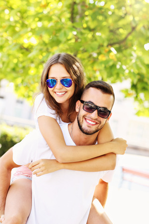 A picture of a happy couple doing piggyback in the parkの写真素材