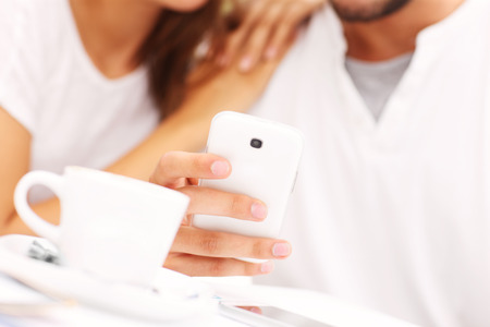 A closeup of hands and smartphone in a cafeの写真素材