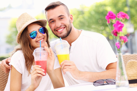 A picture of a happy couple drinking smoothies in an outside cafeの写真素材