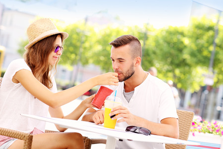 A picture of a happy couple drinking smoothies in an outside cafeの写真素材