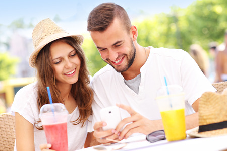 A picture of a happy couple using smartphone in a cafeの写真素材