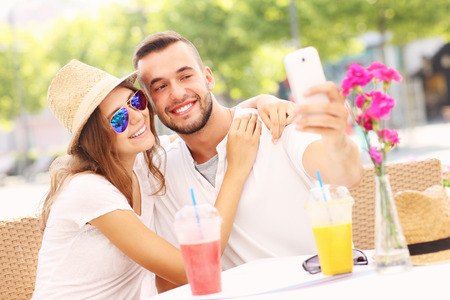A picture of a happy couple taking selfie in a cafeの写真素材