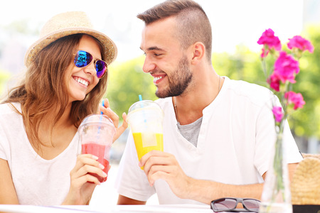 A picture of a happy couple drinking smoothies in an outside cafeの写真素材