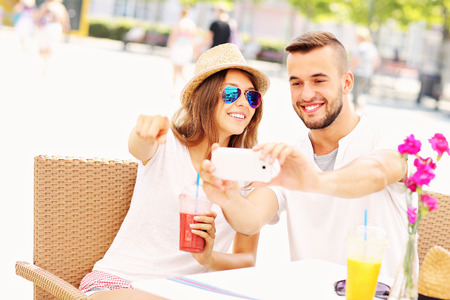 A picture of a happy couple taking pictures in a cafeの写真素材