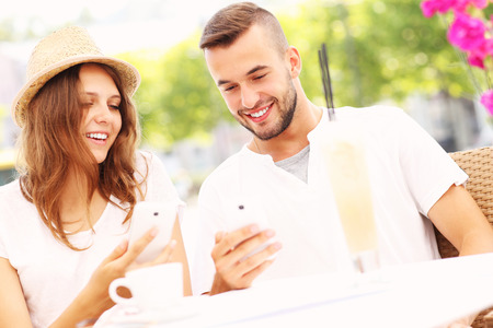 A picture of a happy couple with their smartphones in a cafeの写真素材