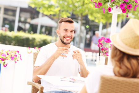 A picture of a young man sitting in the cafe with a date during summer dayの写真素材