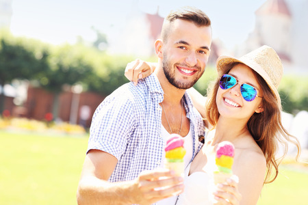 A picture of a joyful couple eating ice-cream cones in the parkの写真素材