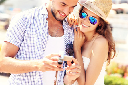 A picture of a young couple checking pictures on the cameraの写真素材