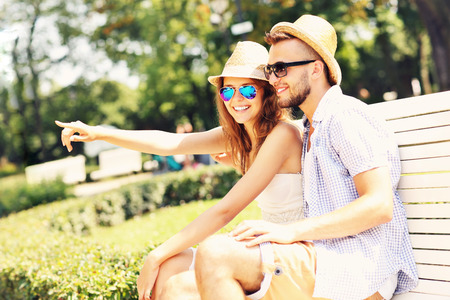 A picture of a young couple sitting on a bench in the parkの写真素材