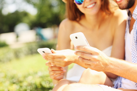 A picture of young people with smartphones in the parkの写真素材