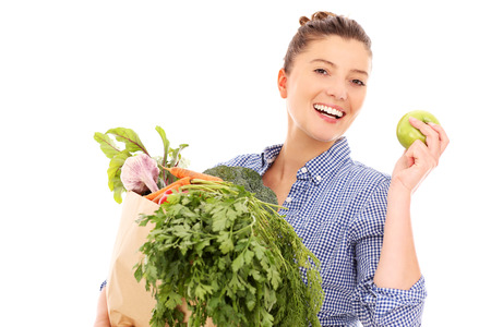 A picture of a happy woman with vegetables and apple over white backgroundの写真素材
