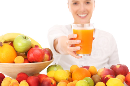 A picture of a happy woman with fruit juice over white backgroundの写真素材