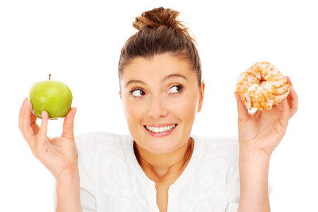 A picture of a woman choosing between apple and donutの写真素材