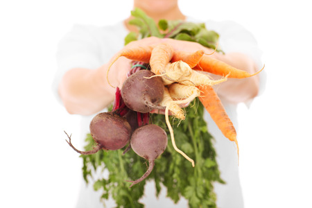 A midsection of a woman holding vegetables over white backgroundの写真素材