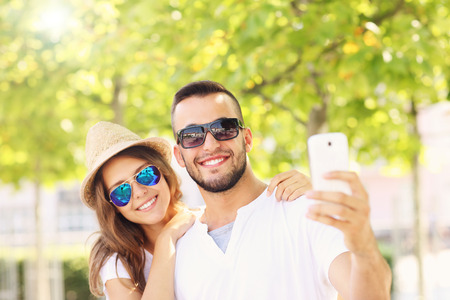 A picture of a happy couple taking selfie in the parkの写真素材
