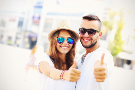 A picture of a happy couple of tourists showing ok in the cityの写真素材