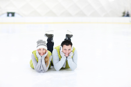 A picture of a happy couple lying on the skating rinkの写真素材