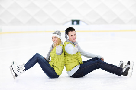 A picture of a happy couple sitting on the skating rinkの写真素材