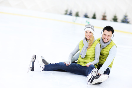 A picture of a happy couple sitting on the skating rinkの写真素材