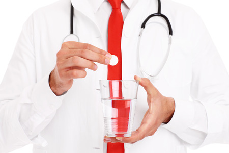 A midsection of a doctor holding pill and glass of waterの写真素材
