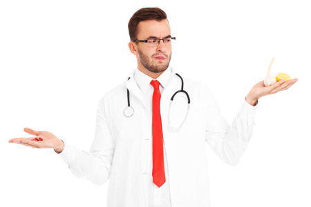 A picture of a doctor holding pills and lemon with garlic over white backgroundの写真素材