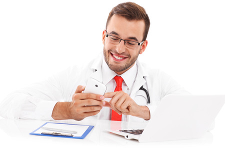A picture of a happy doctor with laptop smartphone and documents sitting in the officeの写真素材