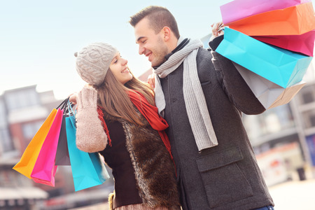 A picture of cheerful young people with shopping bags in the cityの写真素材