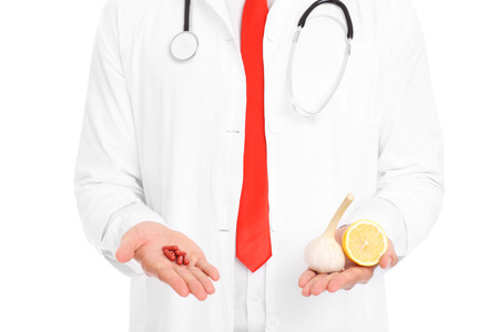 A midsection of a doctor holding pills and lemon with garlicの写真素材