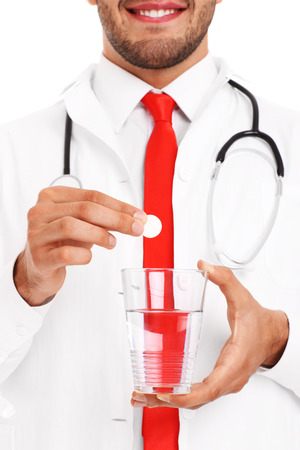 A picture of a doctor holding a pill and glass of waterの写真素材